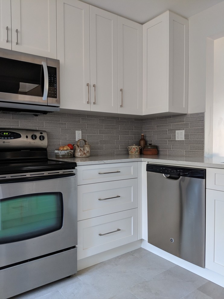 Small transitional u-shaped vinyl floor and beige floor eat-in kitchen photo in Vancouver with a single-bowl sink, shaker cabinets, white cabinets, quartz countertops, gray backsplash, ceramic backsplash, stainless steel appliances, no island and gray countertops
