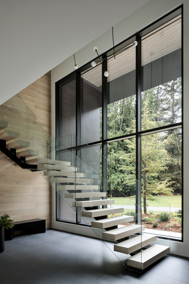 Modern wood floating glass railing staircase in Vancouver with wood walls.