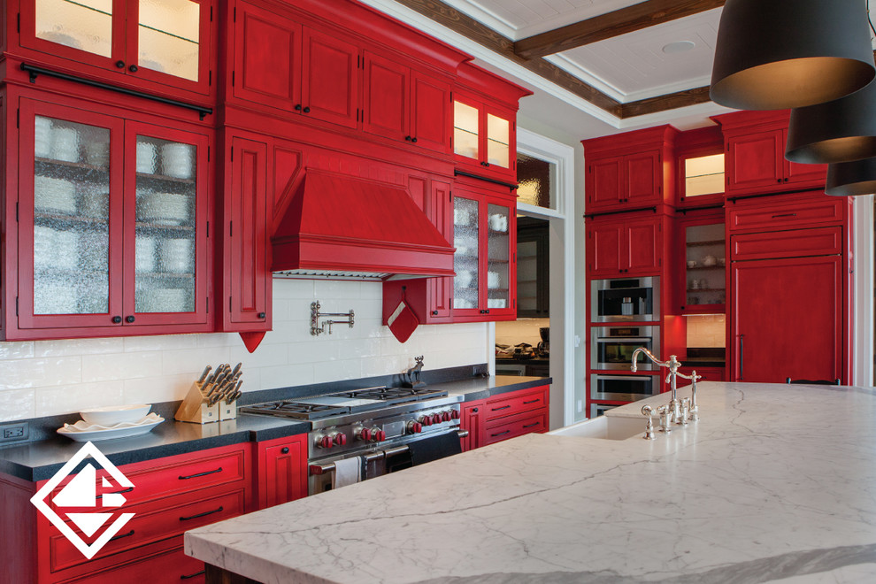 Eat-in kitchen - huge rustic l-shaped medium tone wood floor eat-in kitchen idea with a farmhouse sink, raised-panel cabinets, red cabinets, granite countertops, white backsplash, stainless steel appliances and an island