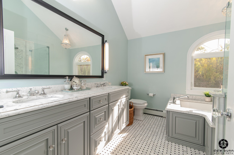 This is an example of a mid-sized traditional master bathroom in Boston with raised-panel cabinets, blue cabinets, an undermount tub, a double shower, a two-piece toilet, black and white tile, stone tile, blue walls, marble floors, an undermount sink and engineered quartz benchtops.