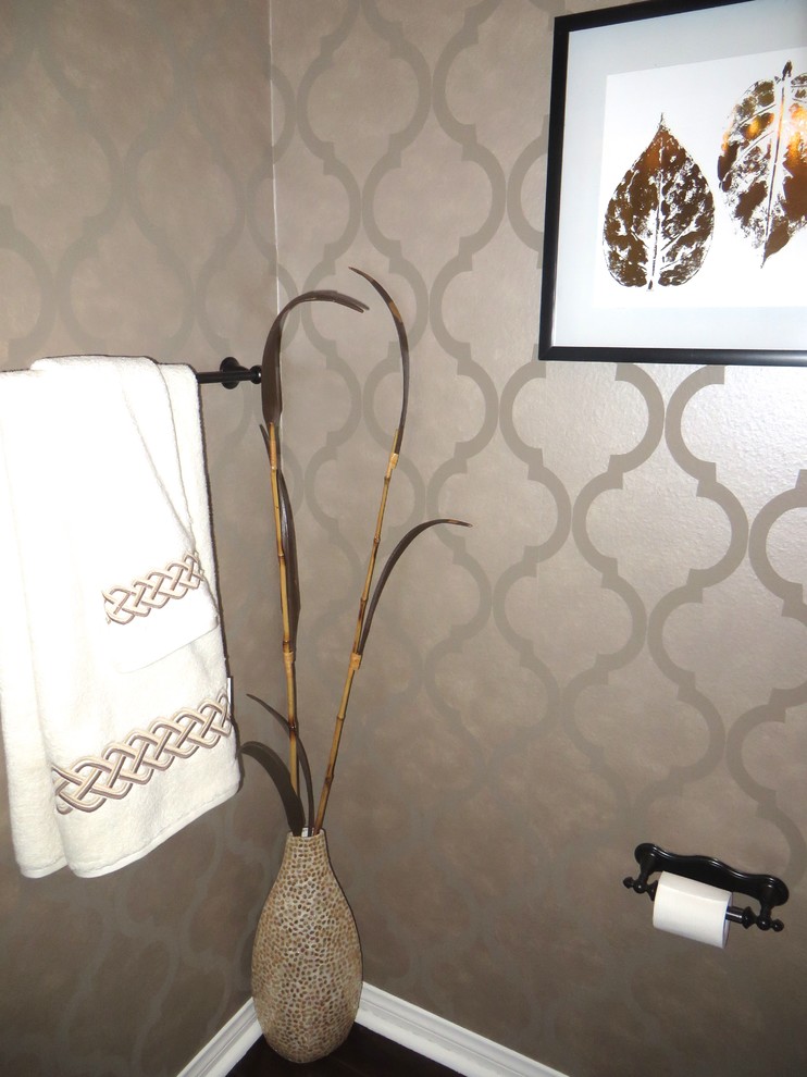 Photo of a small traditional powder room in Orange County with a two-piece toilet, beige walls, dark hardwood floors, a pedestal sink and brown floor.
