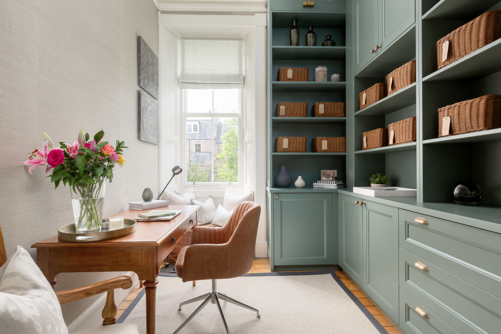 This is an example of a transitional craft room in Edinburgh with light hardwood floors, a freestanding desk and wallpaper.