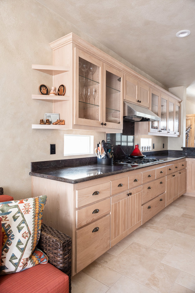 This is an example of a mid-sized u-shaped eat-in kitchen in San Luis Obispo with a drop-in sink, recessed-panel cabinets, light wood cabinets, granite benchtops, black appliances, limestone floors, with island, beige floor and black benchtop.