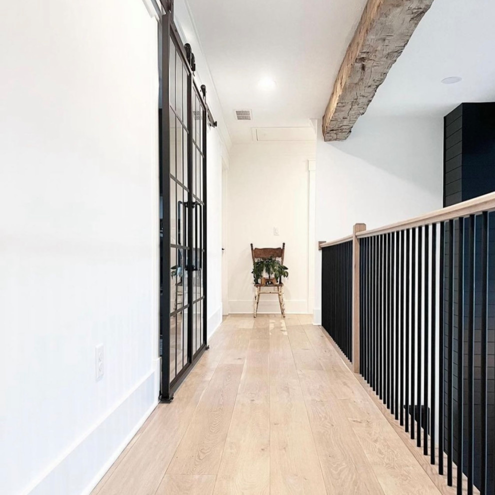Inspiration for a mid-sized modern hallway in Los Angeles with white walls, light hardwood floors, multi-coloured floor, exposed beam and panelled walls.