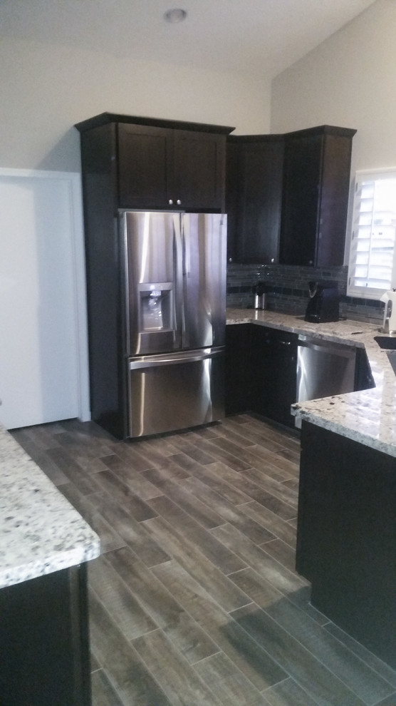 Photo of a small transitional u-shaped kitchen in Phoenix with an undermount sink, shaker cabinets, dark wood cabinets, granite benchtops, grey splashback, glass tile splashback, stainless steel appliances, ceramic floors and with island.