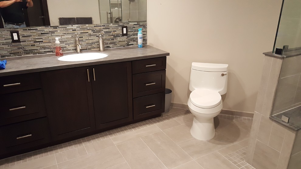 Design ideas for a mid-sized contemporary 3/4 bathroom in Detroit with shaker cabinets, dark wood cabinets, an alcove shower, a one-piece toilet, gray tile, matchstick tile, beige walls, porcelain floors, an undermount sink, concrete benchtops, beige floor and a hinged shower door.