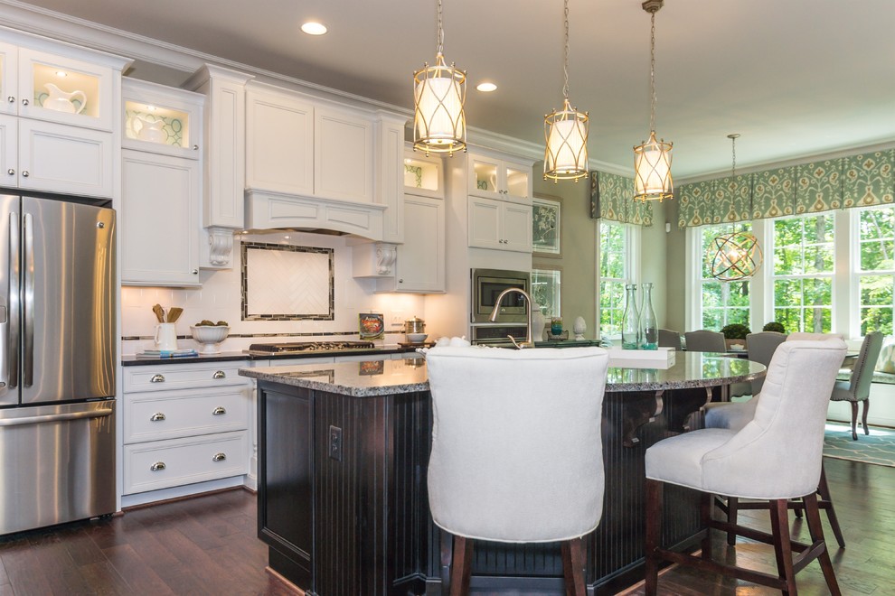 This is an example of a transitional l-shaped kitchen in Raleigh with a double-bowl sink, white cabinets, stainless steel appliances and with island.