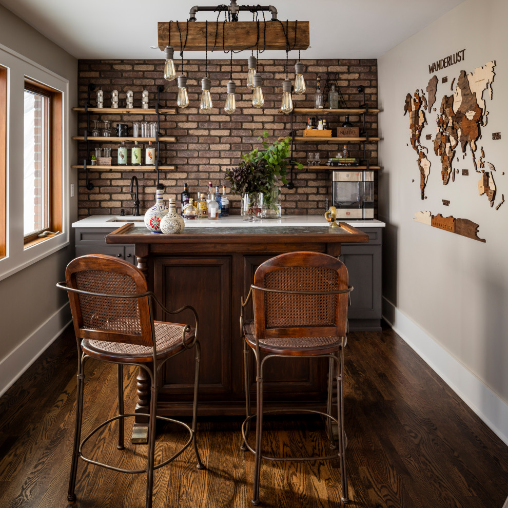 Design ideas for a traditional galley seated home bar in Seattle with an undermount sink, recessed-panel cabinets, grey cabinets, quartz benchtops, brick splashback, dark hardwood floors, brown floor, white benchtop and brown splashback.
