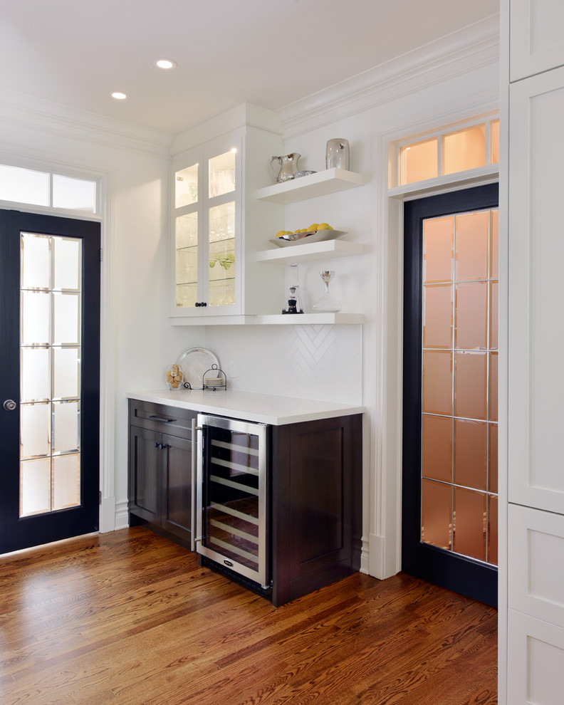 Home bar - large traditional medium tone wood floor home bar idea in Ottawa with shaker cabinets, white backsplash, dark wood cabinets and white countertops