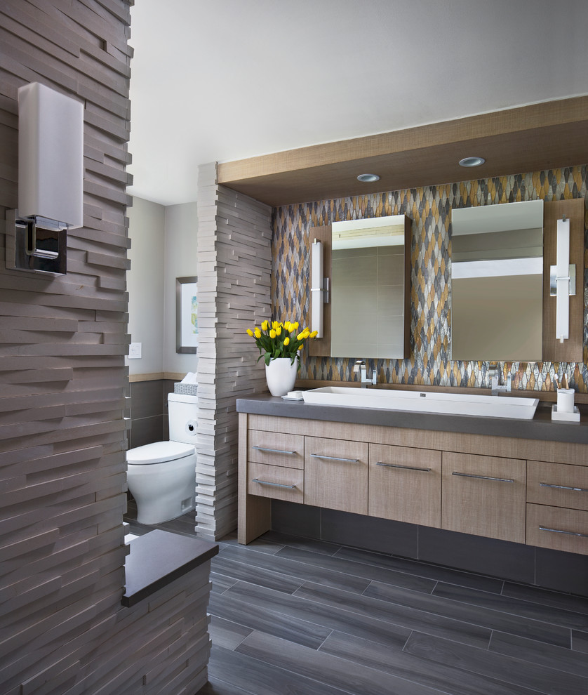 Inspiration for a contemporary master bathroom in Detroit with a trough sink, flat-panel cabinets, beige cabinets, engineered quartz benchtops, an alcove tub, a curbless shower, a two-piece toilet, multi-coloured tile, glass tile, grey walls, porcelain floors and grey benchtops.