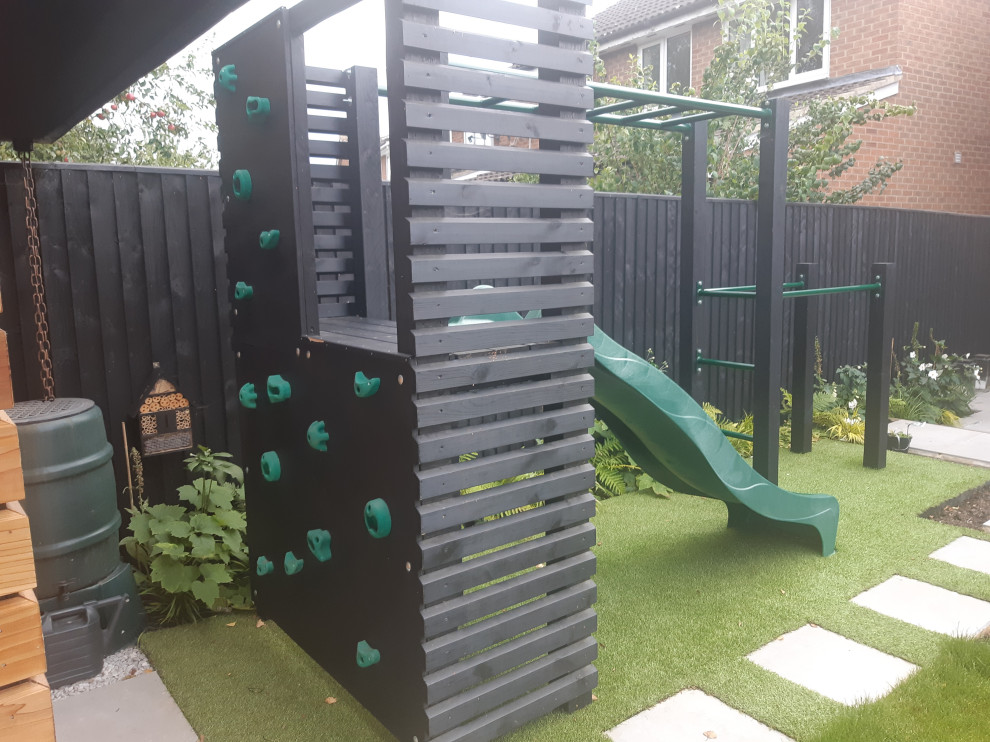 Photo of a small contemporary back partial sun garden for summer in Oxfordshire with a climbing frame and a wood fence.