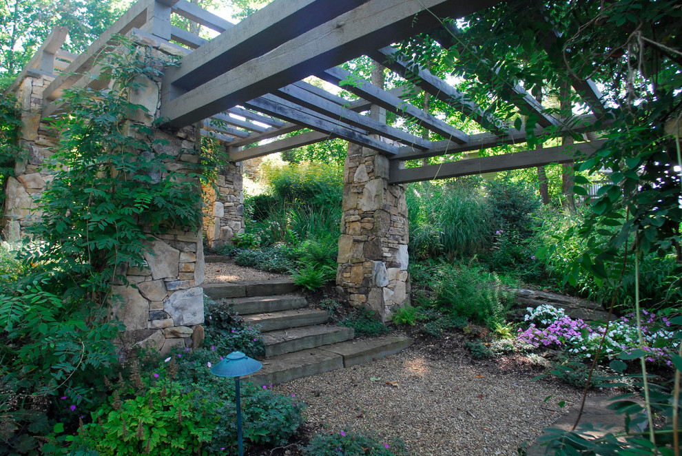 This is an example of an expansive traditional sloped shaded formal garden for spring in Charlotte with gravel.