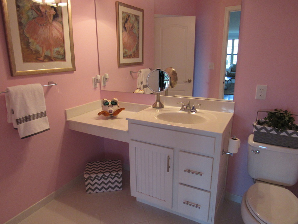 Inspiration for a modern kids bathroom in Philadelphia with beaded inset cabinets, white cabinets, a one-piece toilet, white tile, porcelain tile, pink walls, porcelain floors, an integrated sink and solid surface benchtops.