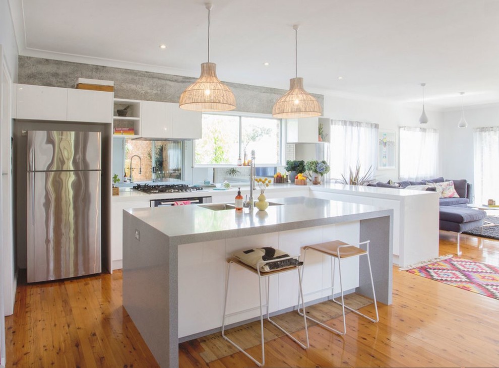 Large scandinavian l-shaped eat-in kitchen in Other with flat-panel cabinets, white cabinets, stainless steel appliances, light hardwood floors, with island, a double-bowl sink, quartz benchtops, white splashback and glass tile splashback.