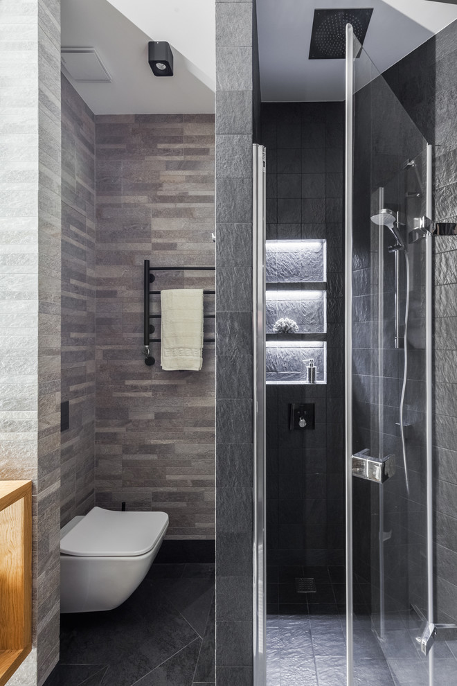 Photo of a small contemporary 3/4 bathroom in Other with an alcove shower, a wall-mount toilet, gray tile, porcelain tile, porcelain floors, black floor and a hinged shower door.