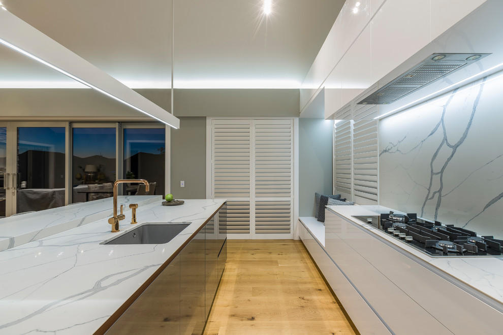This is an example of a mid-sized contemporary l-shaped eat-in kitchen in Auckland with white cabinets, with island and white benchtop.