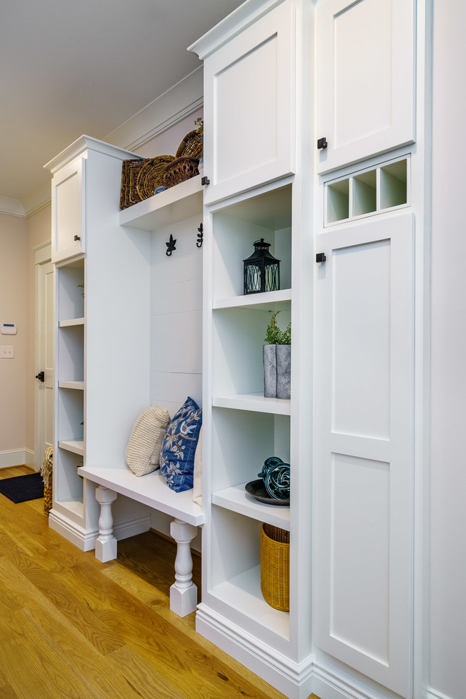 Mudroom - large transitional medium tone wood floor and brown floor mudroom idea with white walls and a medium wood front door