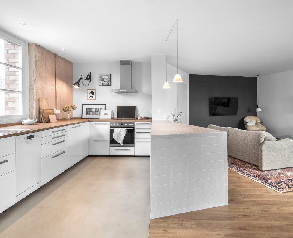 Inspiration for an expansive eclectic u-shaped eat-in kitchen in Hamburg with a single-bowl sink, flat-panel cabinets, white cabinets, wood benchtops, pink splashback, stone slab splashback, concrete floors, a peninsula and grey floor.