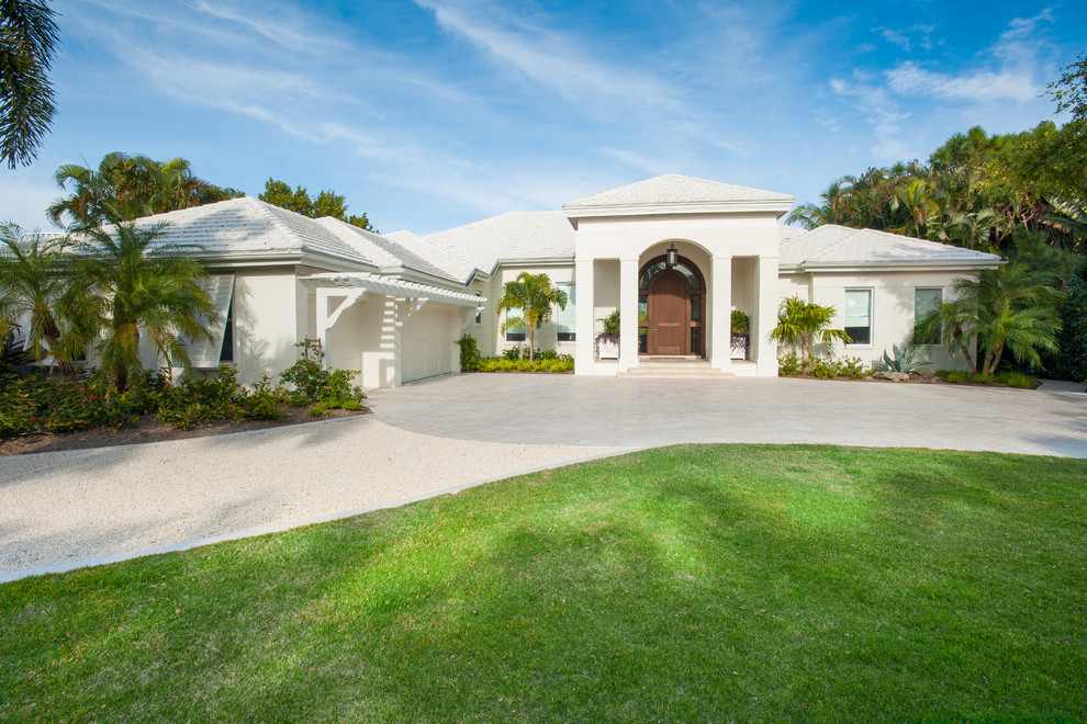 This is an example of a large beach style one-storey white exterior in Tampa with a hip roof.