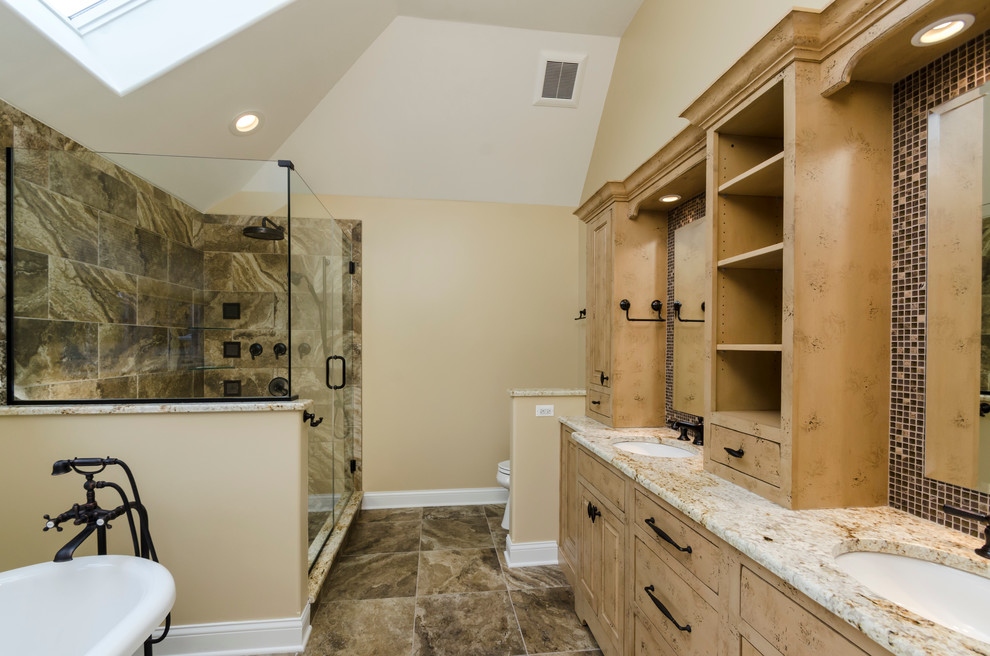 Large mountain style master brown tile and porcelain tile porcelain tile freestanding bathtub photo in Chicago with an undermount sink, raised-panel cabinets, light wood cabinets, granite countertops, a two-piece toilet and beige walls