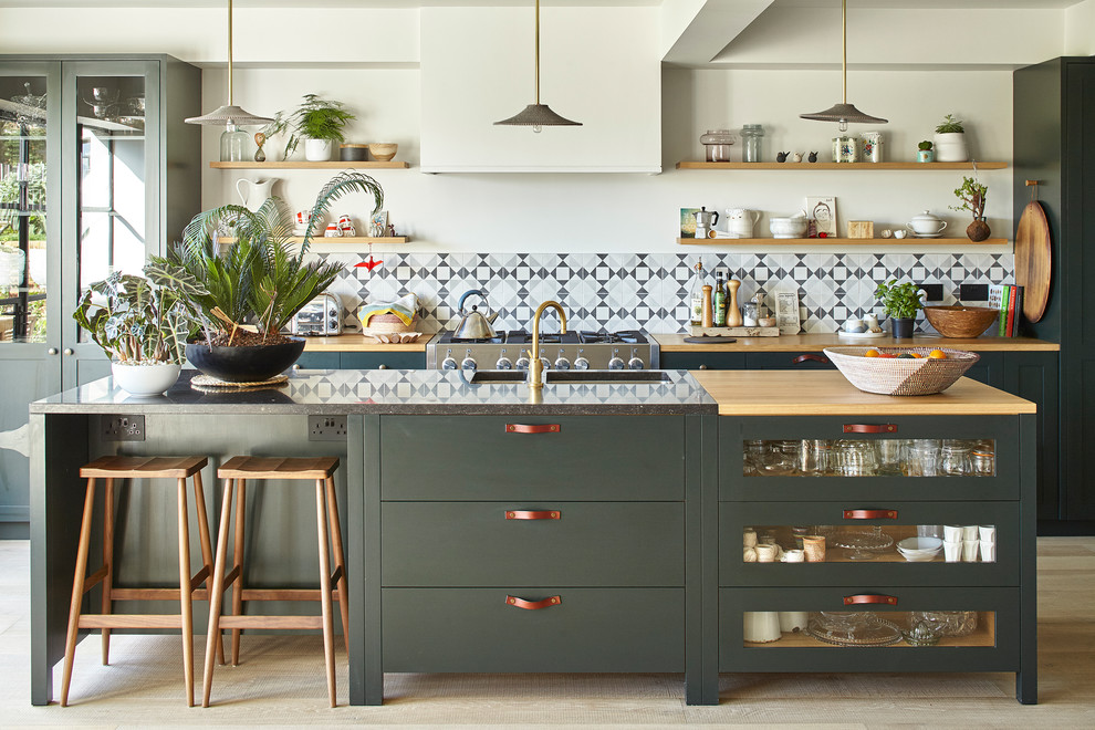 This is an example of a transitional galley kitchen in Sussex with a double-bowl sink, shaker cabinets, green cabinets, wood benchtops, grey splashback, mosaic tile splashback, light hardwood floors, with island and beige floor.