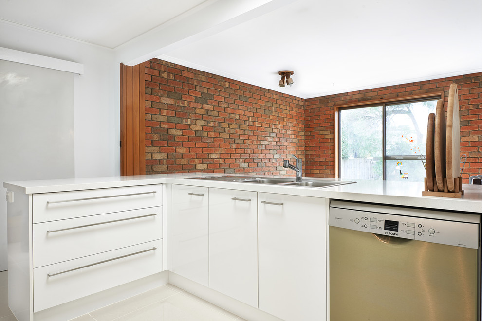 Mid-sized contemporary galley open plan kitchen in Melbourne with a double-bowl sink, flat-panel cabinets, white cabinets, quartz benchtops, multi-coloured splashback, glass sheet splashback, stainless steel appliances, porcelain floors and a peninsula.
