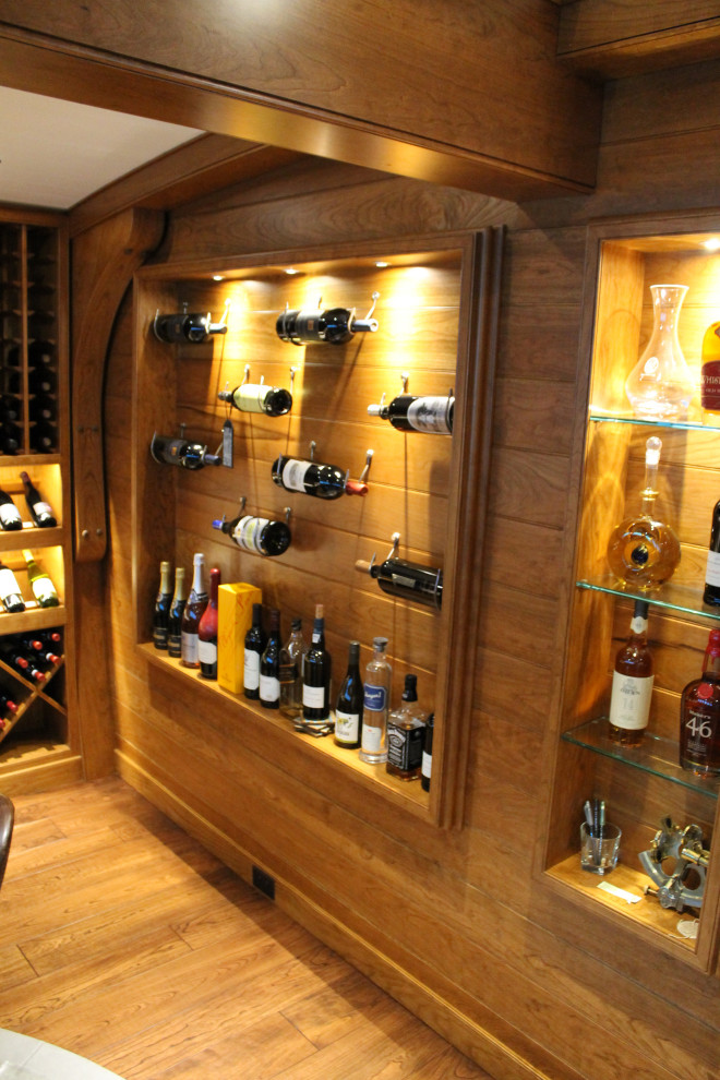 Photo of a mid-sized beach style wine cellar in Chicago with light hardwood floors, display racks and brown floor.