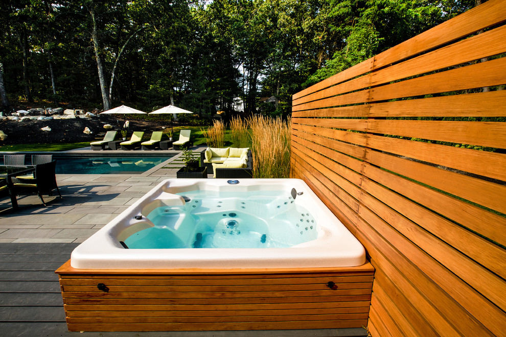 Photo of a mid-sized contemporary rectangular pool in Boston with natural stone pavers.