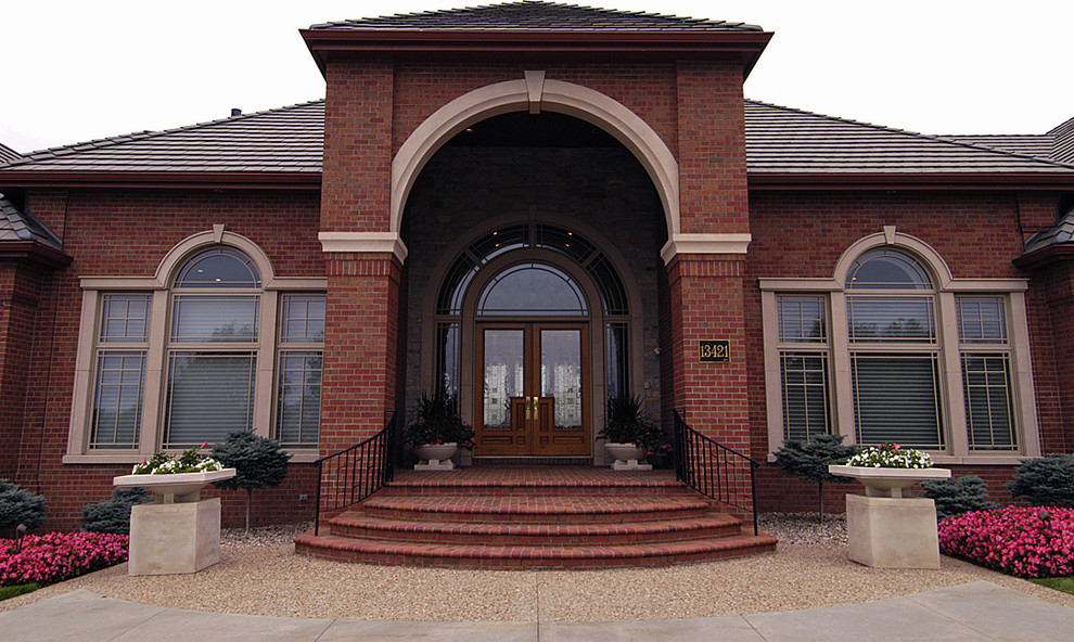 This is an example of an expansive transitional one-storey brick red exterior in Omaha.