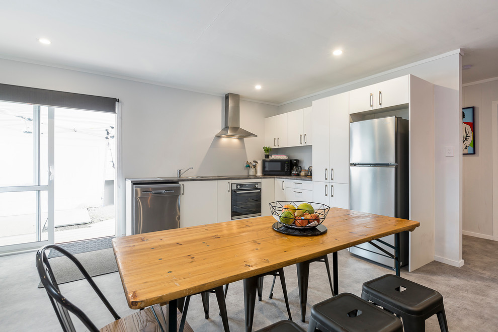 Design ideas for a mid-sized modern l-shaped open plan kitchen in Auckland with a drop-in sink, flat-panel cabinets, white cabinets, solid surface benchtops, stainless steel appliances, linoleum floors, no island, multi-coloured floor and multi-coloured benchtop.