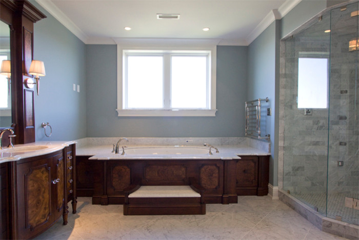 This is an example of a large traditional master bathroom in Louisville with an integrated sink, recessed-panel cabinets, dark wood cabinets, marble benchtops, a drop-in tub, a corner shower, a one-piece toilet, white tile, ceramic tile, blue walls and ceramic floors.