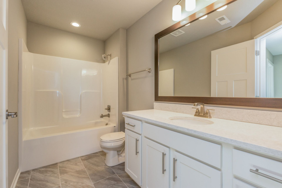 Large transitional master multicolored tile and ceramic tile ceramic tile and multicolored floor tub/shower combo photo with shaker cabinets, white cabinets, a two-piece toilet, beige walls, an undermount sink, quartz countertops and white countertops