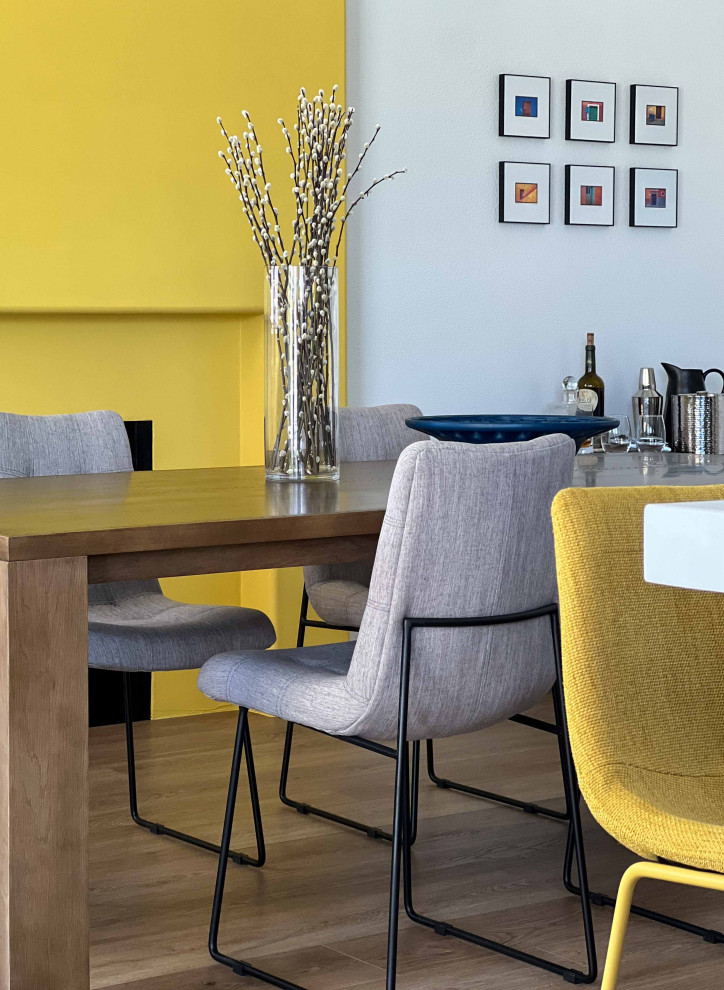 Свежая идея для дизайна: столовая в стиле ретро с желтыми стенами, стандартным камином и фасадом камина из штукатурки - отличное фото интерьера