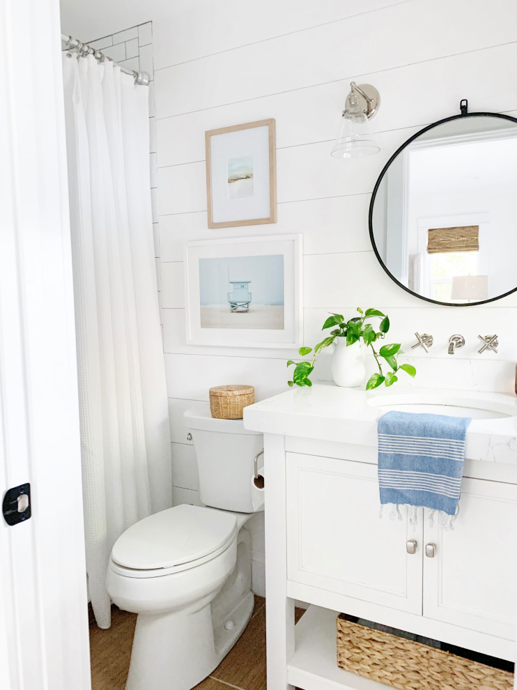 This is an example of a mid-sized beach style 3/4 bathroom in Orlando with recessed-panel cabinets, white cabinets, a shower/bathtub combo, a two-piece toilet, white walls, an undermount sink, beige floor, a shower curtain, white benchtops, a single vanity, a built-in vanity and planked wall panelling.