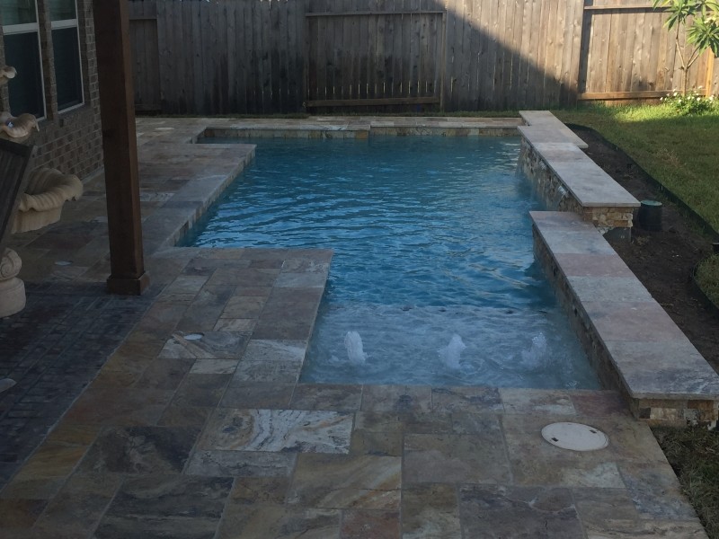 Inspiration for a mid-sized transitional backyard custom-shaped pool in Houston with a water feature and natural stone pavers.