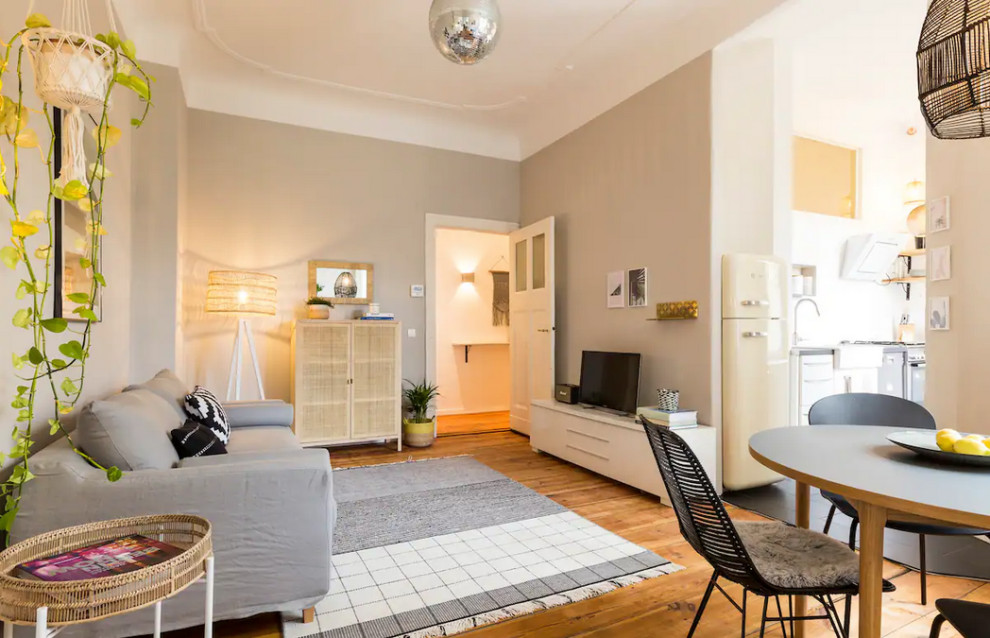 Mittelgroßes, Offenes Nordisches Wohnzimmer mit beiger Wandfarbe, hellem Holzboden, freistehendem TV und Ziegelwänden in Berlin