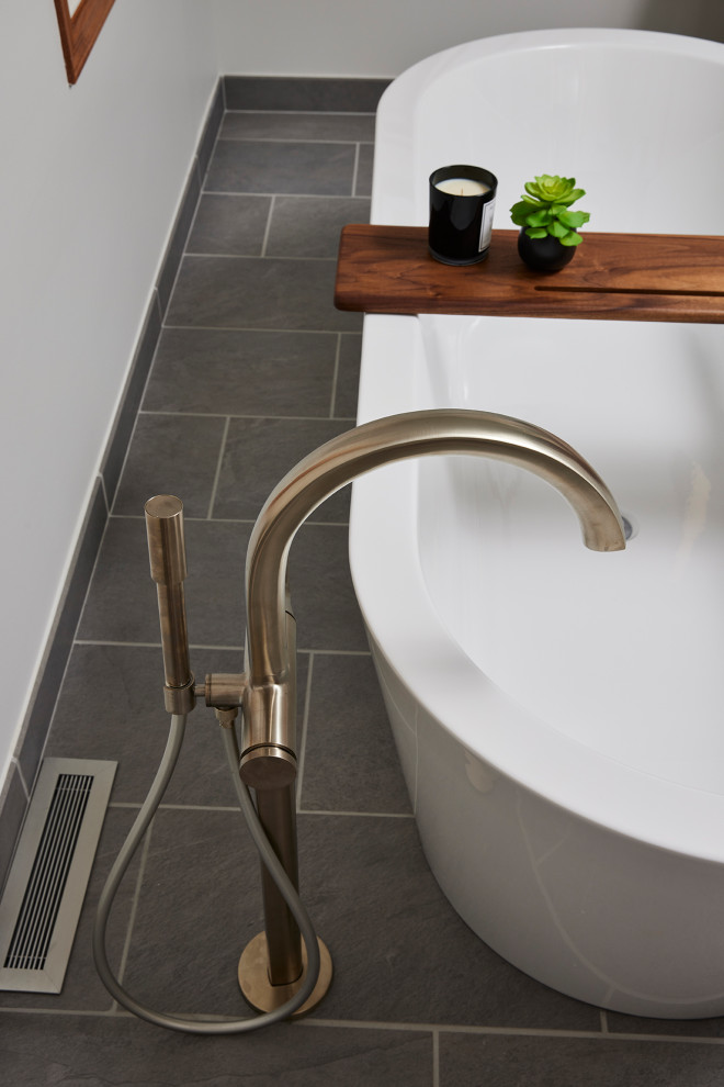 Immagine di una grande stanza da bagno moderna con vasca freestanding, doccia ad angolo, pareti bianche, pavimento in gres porcellanato, pavimento grigio e porta doccia a battente