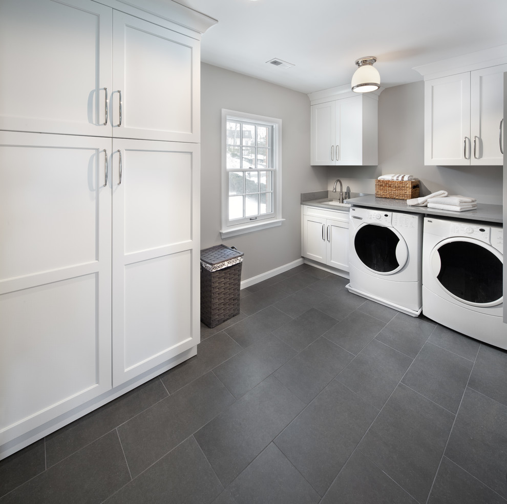 Photo of an expansive transitional l-shaped dedicated laundry room in DC Metro with recessed-panel cabinets, white cabinets, wood benchtops, grey walls, ceramic floors, a side-by-side washer and dryer and an undermount sink.