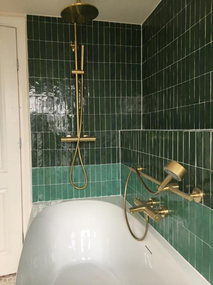 Cette image montre une salle de bain principale méditerranéenne de taille moyenne avec une baignoire d'angle, WC suspendus, un carrelage vert, un mur beige, un sol en galet, un lavabo posé, un sol blanc, une fenêtre et meuble simple vasque.