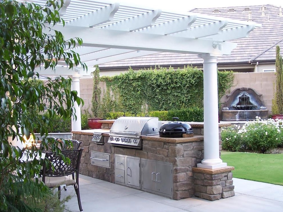 Example of a mid-sized tuscan backyard concrete patio kitchen design with a pergola