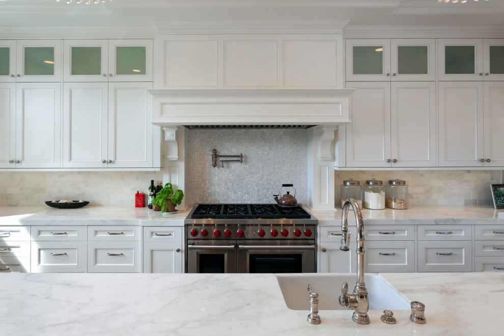 This is an example of an expansive traditional u-shaped kitchen/diner in Santa Barbara with a submerged sink, raised-panel cabinets, white cabinets, marble worktops, white splashback, marble splashback, stainless steel appliances, medium hardwood flooring, an island, brown floors, white worktops and a coffered ceiling.