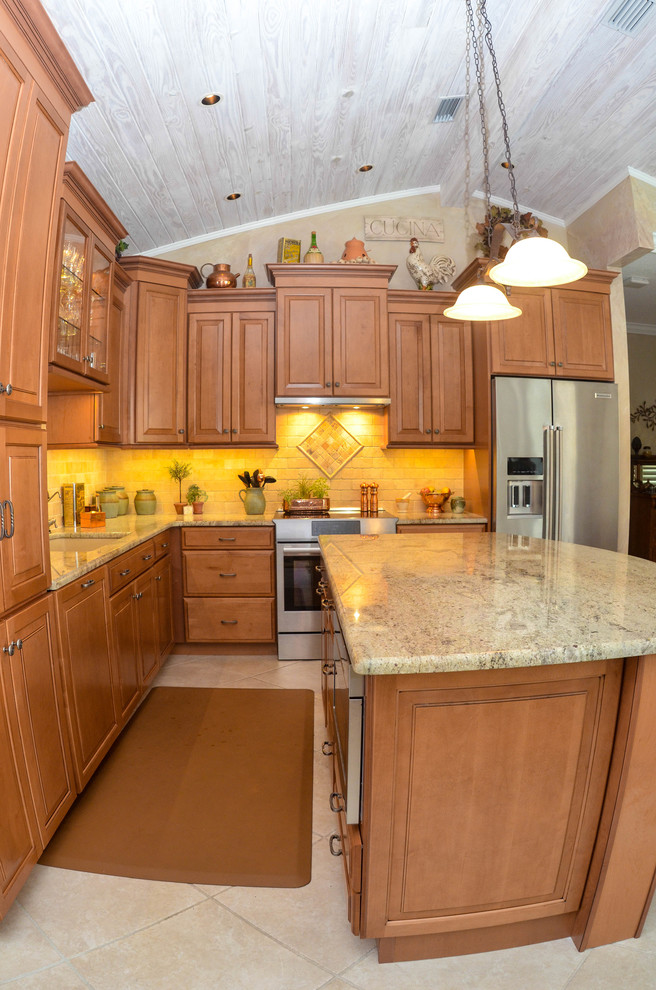 Mid-sized mountain style l-shaped travertine floor open concept kitchen photo in Tampa with an undermount sink, raised-panel cabinets, dark wood cabinets, limestone countertops, beige backsplash, stone tile backsplash, stainless steel appliances and an island