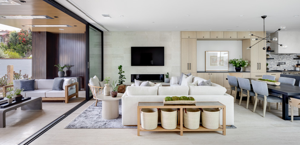 This is an example of a large contemporary open concept living room in Orange County with white walls, porcelain floors, a ribbon fireplace, a stone fireplace surround, a wall-mounted tv and beige floor.