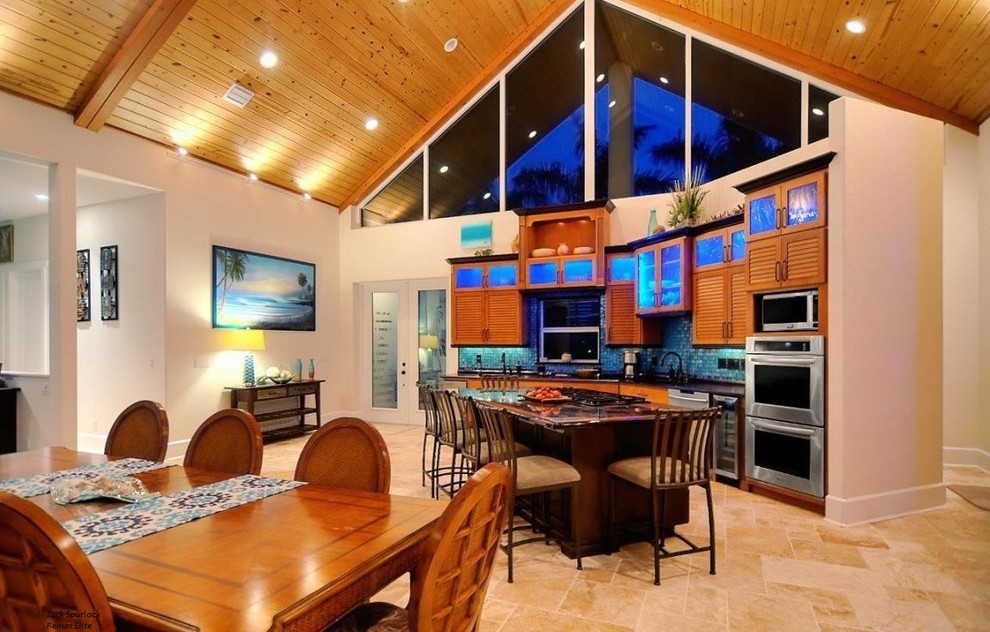 Photo of a mid-sized tropical u-shaped open plan kitchen in Orlando with an undermount sink, louvered cabinets, medium wood cabinets, granite benchtops, blue splashback, mosaic tile splashback, stainless steel appliances, limestone floors and with island.