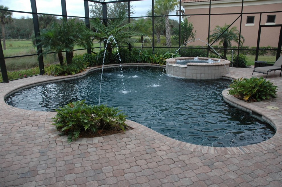 Photo of a mid-sized traditional backyard custom-shaped lap pool in San Diego with a water feature and concrete pavers.