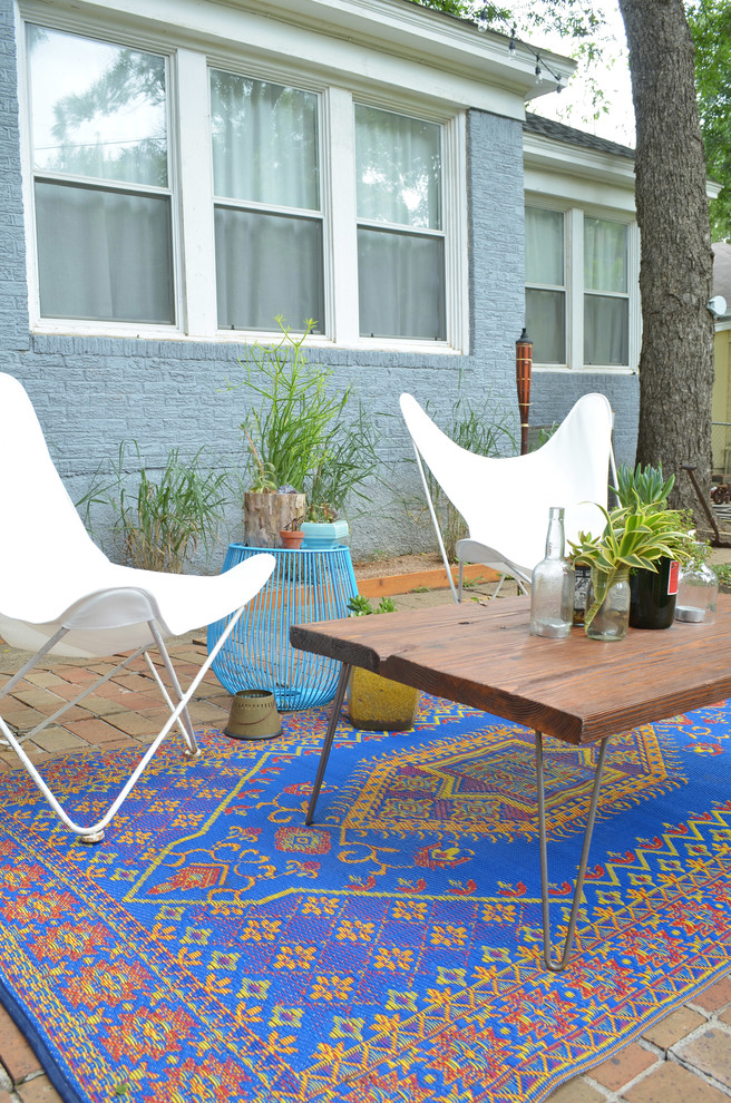 This is an example of an eclectic patio in Dallas with brick pavers and no cover.