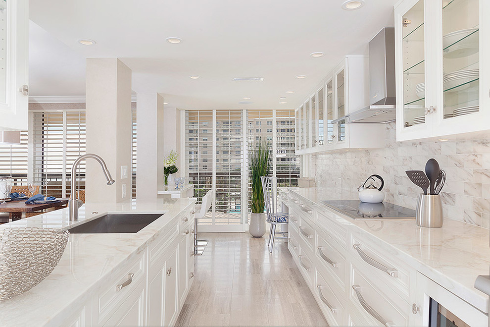 Eat-in kitchen - large transitional galley light wood floor and beige floor eat-in kitchen idea in Miami with white cabinets, glass-front cabinets, stainless steel appliances, an island, a drop-in sink, marble countertops, multicolored backsplash, marble backsplash and white countertops
