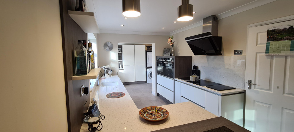 This is an example of a mid-sized modern l-shaped open plan kitchen in West Midlands with flat-panel cabinets, white cabinets, granite benchtops and white benchtop.