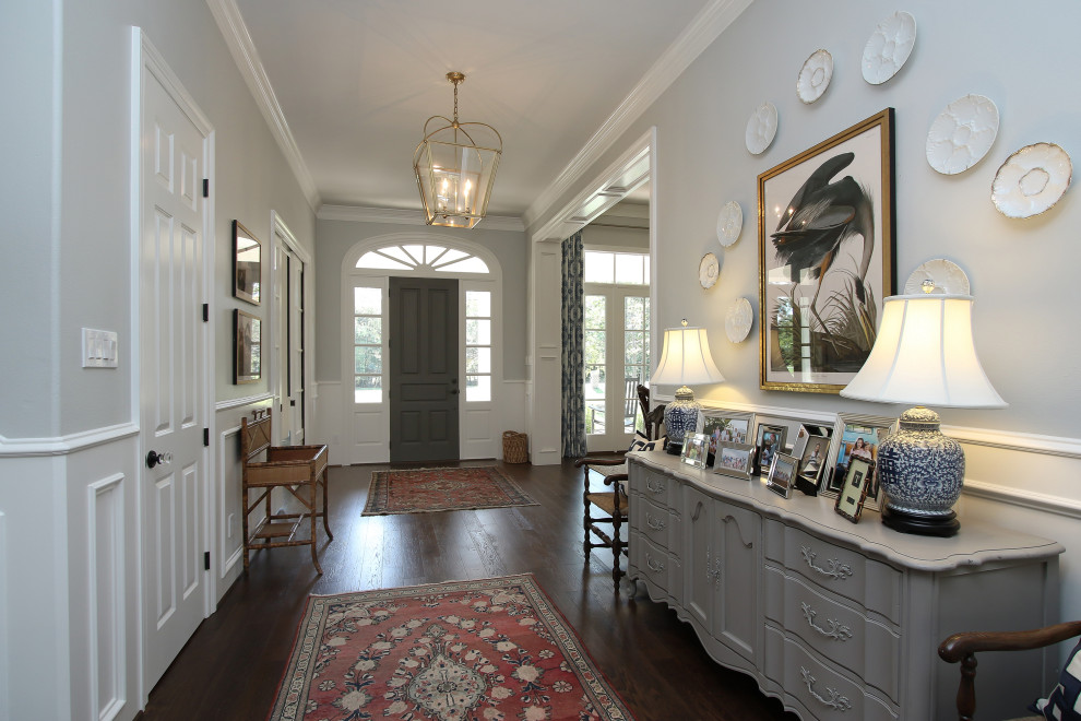 Großes Klassisches Foyer mit Einzeltür, dunkler Holzhaustür, grauer Wandfarbe, dunklem Holzboden, braunem Boden und vertäfelten Wänden in Houston