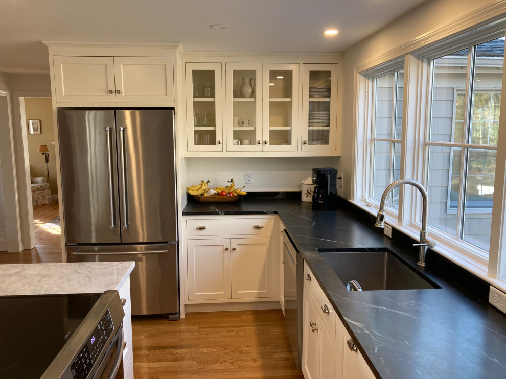 Foto på ett mellanstort vintage grå kök, med en enkel diskho, skåp i shakerstil, vita skåp, bänkskiva i kvarts, svart stänkskydd, stänkskydd i sten, rostfria vitvaror, mellanmörkt trägolv, en köksö och brunt golv